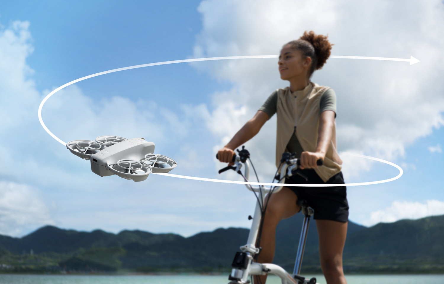 Mujer en bicicleta con dron volando en el aire, contra cielo.