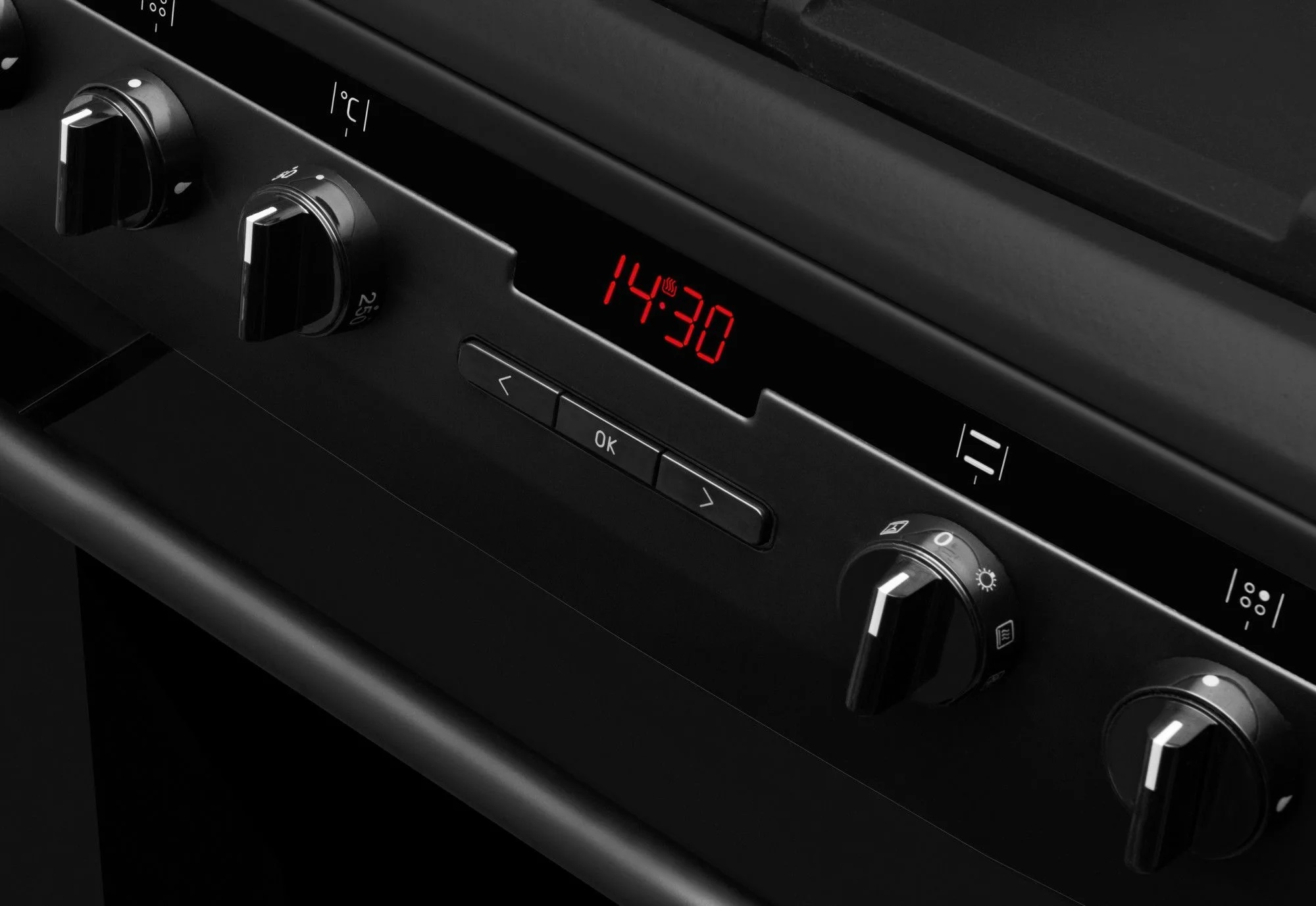 Czarny panel kuchenki z pokrętłami, zegar cyfrowy pokazujący 14:30 i czarne tło.
