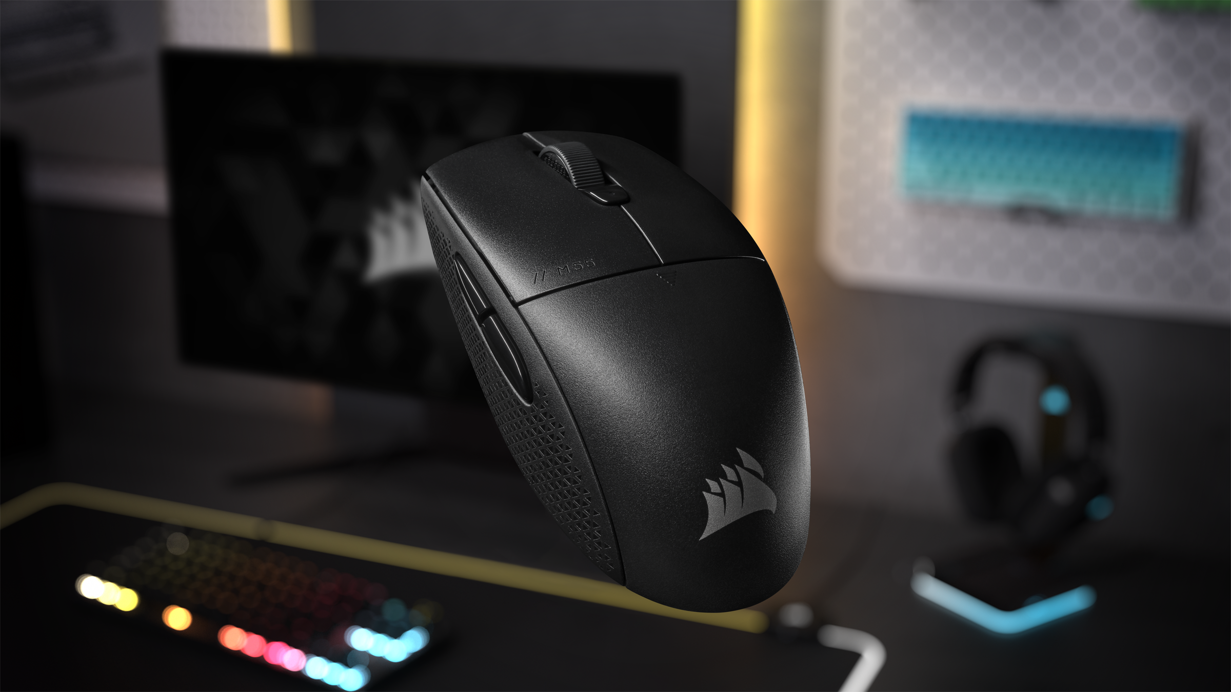 Eine schwarze kabellose Maus mit Logo, auf einem Schreibtisch mit Tastatur und Kopfhörern.