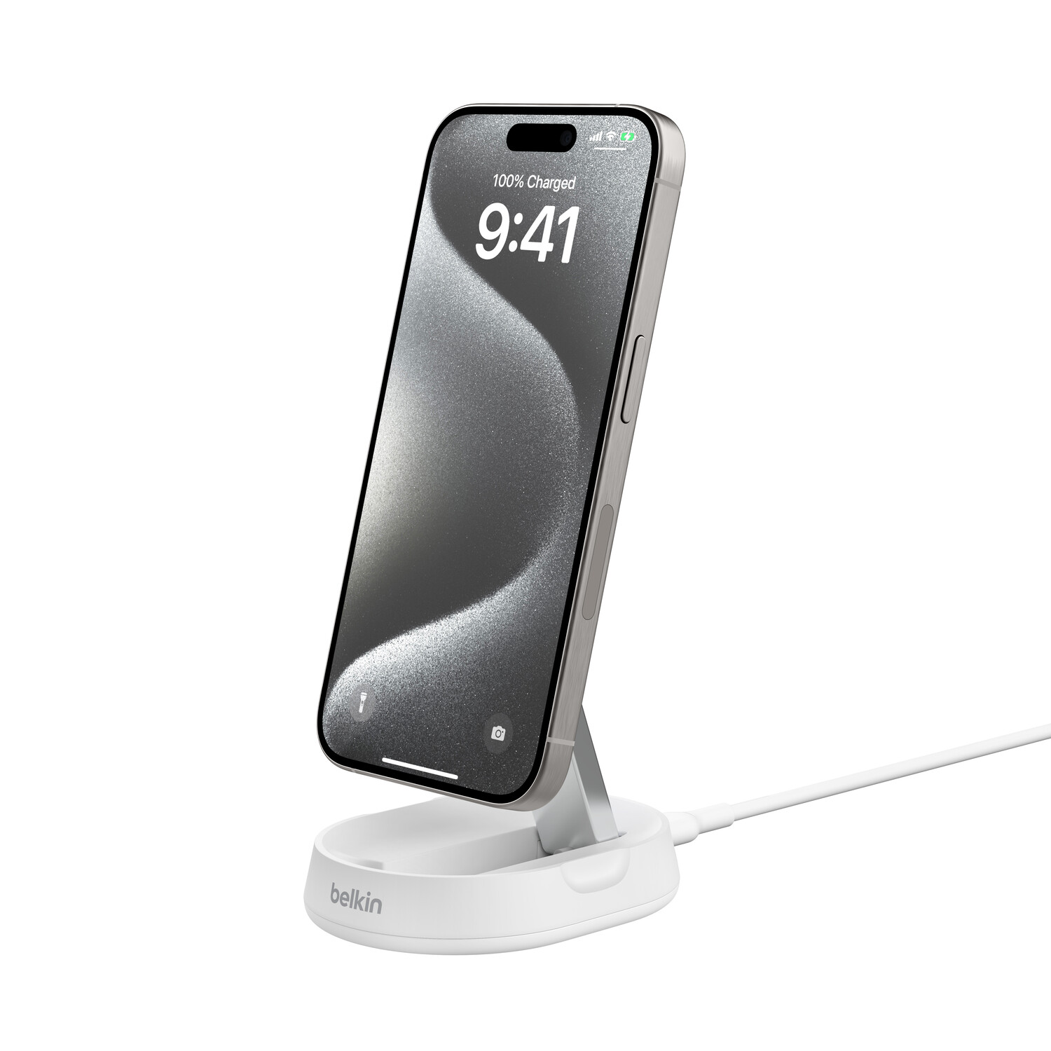 iPhone argenté en charge sur un support Belkin blanc. L'écran affiche l'heure et la batterie.