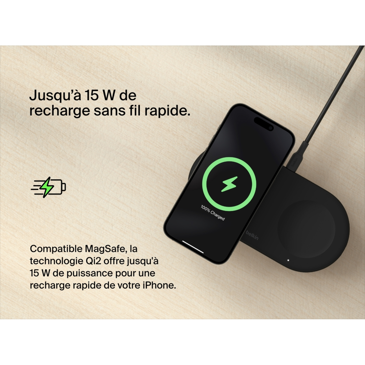 Téléphone noir sur un chargeur sans fil. Le téléphone affiche 100% chargé. Surface en bois.