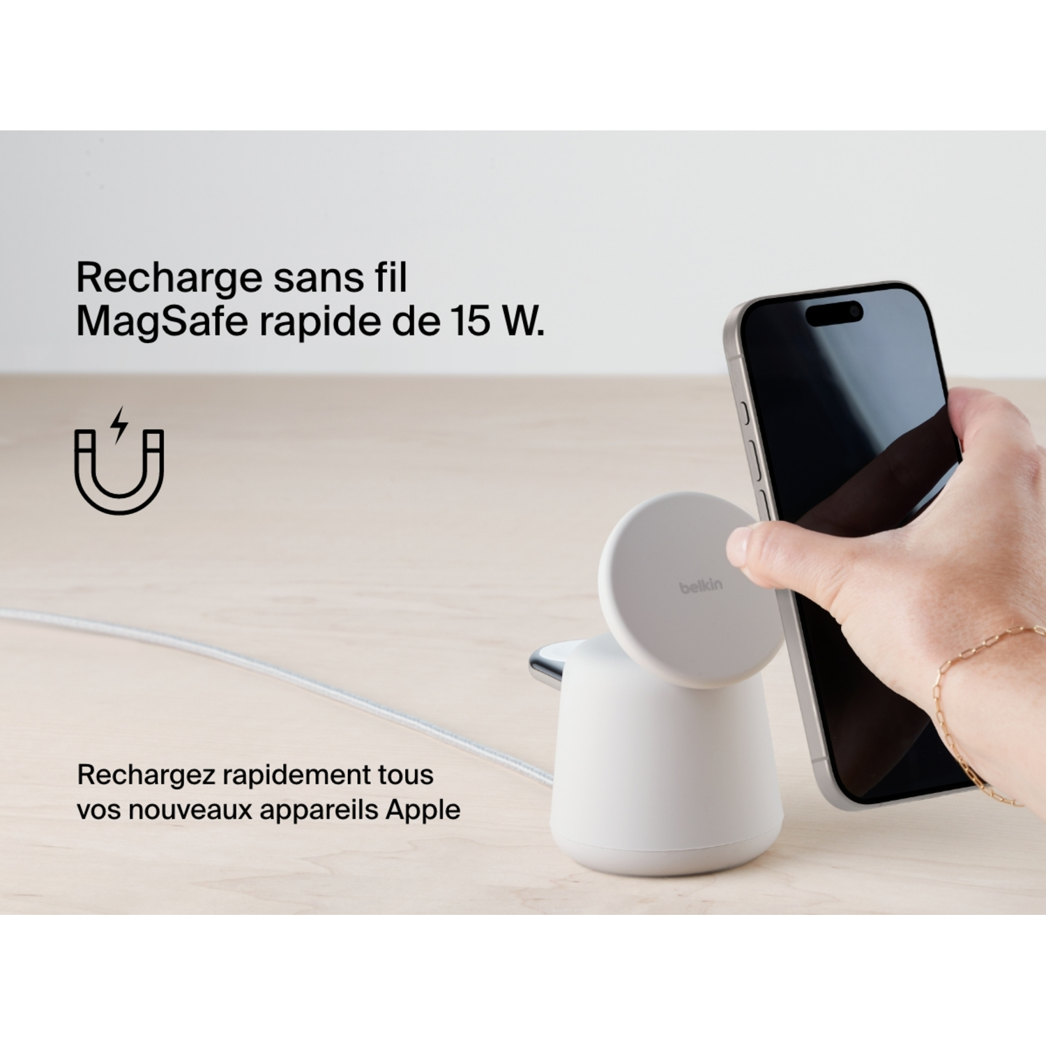 Main tenant un téléphone près d'un socle de chargement sans fil.