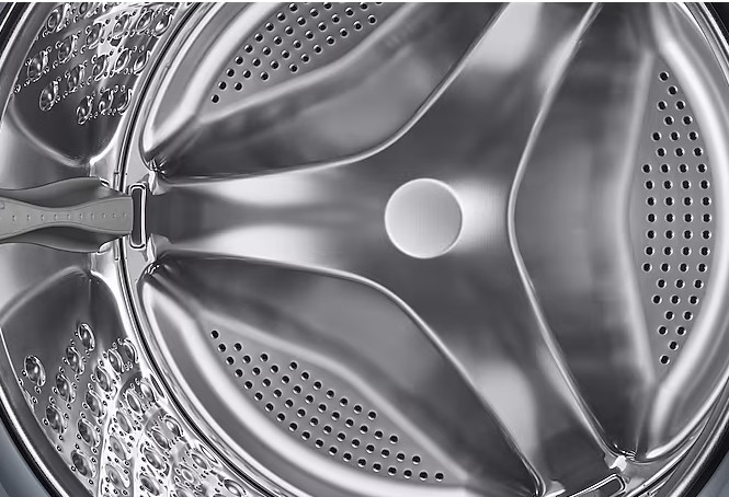 Wnętrze bębna pralki, z błyszczącą powierzchnią przypominającą stal.