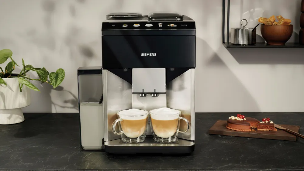 Kávéfőző két latte csészével és süteményekkel.