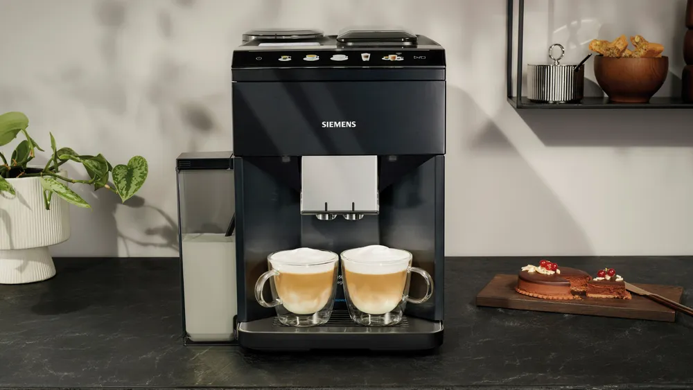 Siemens kávéfőző két csésze kávéval és két desszerttel egy fa deszkán.