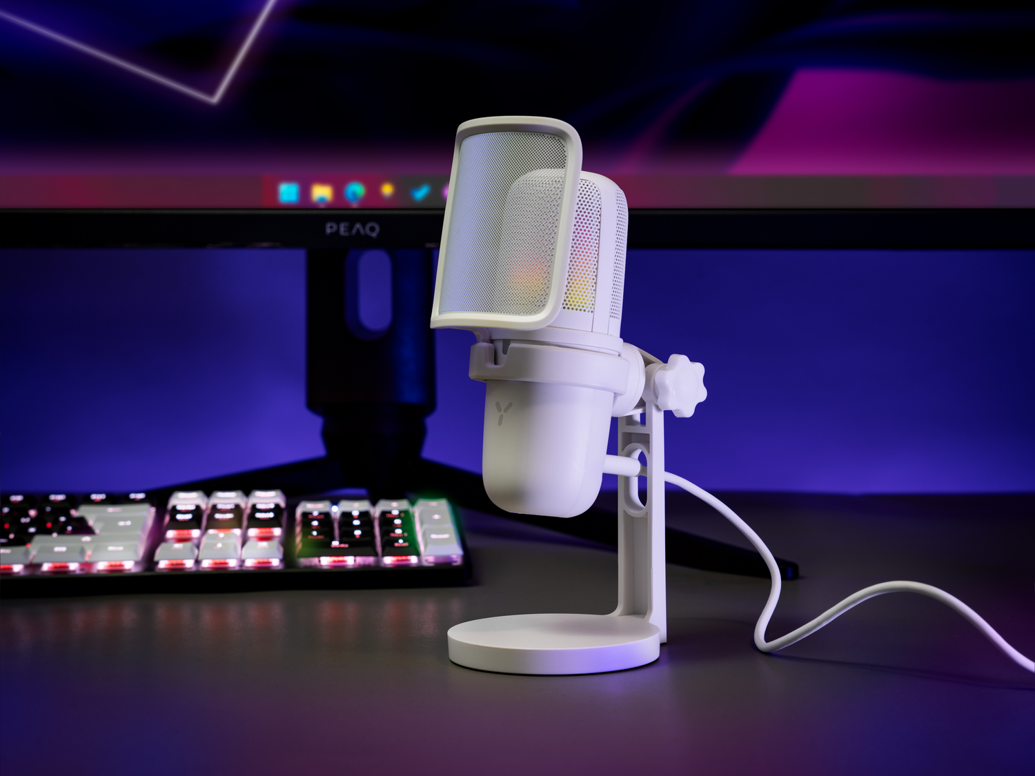 Micrófono blanco con soporte y filtro antipop. Un teclado y un monitor están en el fondo.