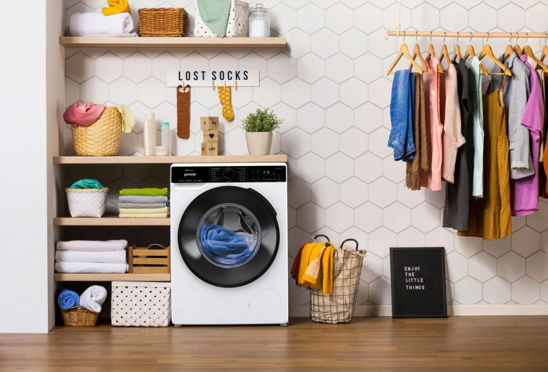 Mosókonyha mosógéppel, polcokkal és ruhákkal. Egy tábla azt mondja: 'LOST SOCKS'.