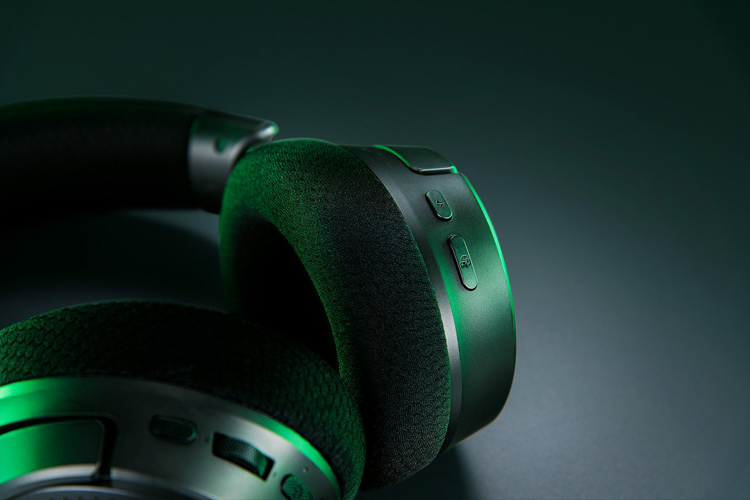Primo piano di cuffie da gioco nere con illuminazione verde.