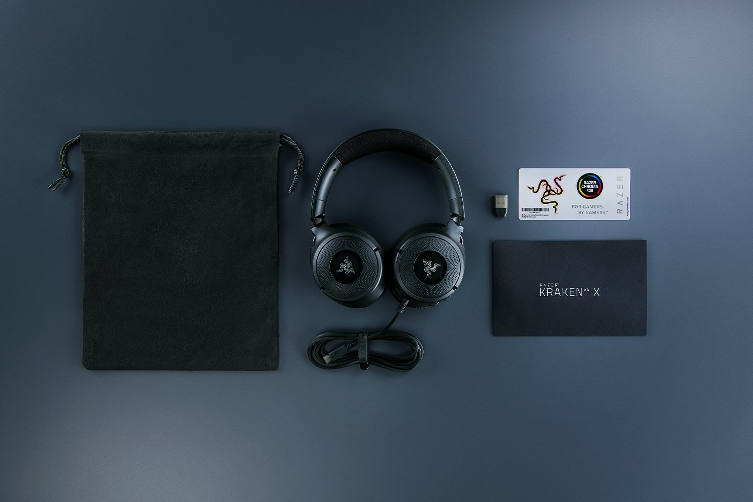 Cuffie, borsa, carta, dongle e libretto neri su una superficie scura.