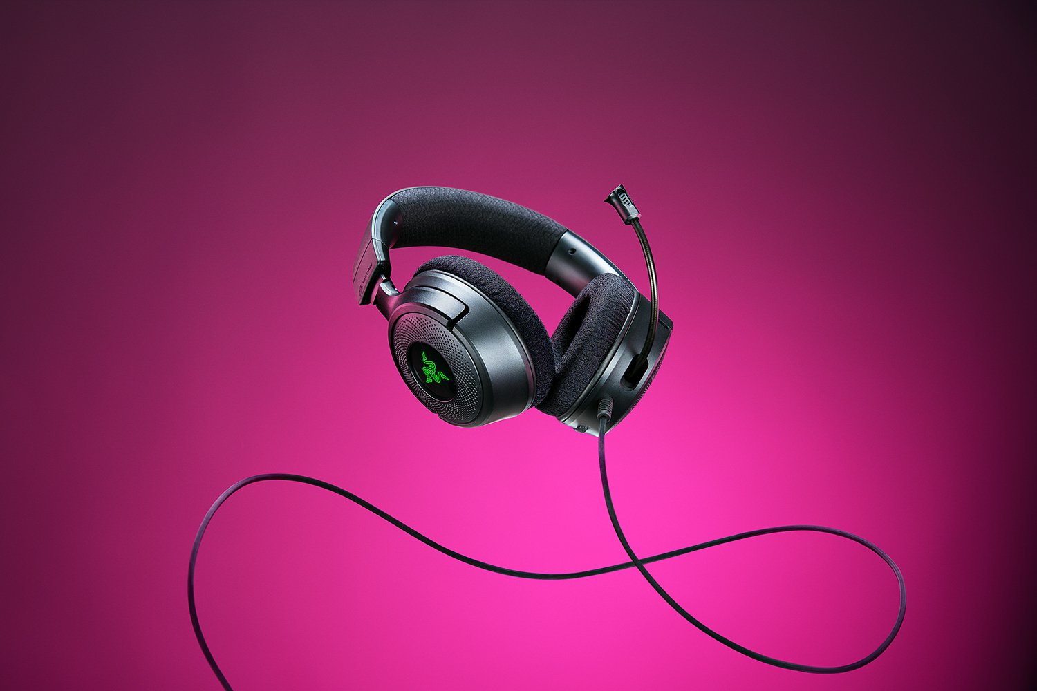 Cuffie da gioco nere con logo verde. Sfondo rosa. Il cavo pende.