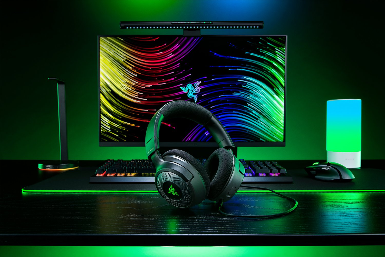 Configurazione gaming con cuffie, monitor, tastiera, mouse e luci. Tema verde.