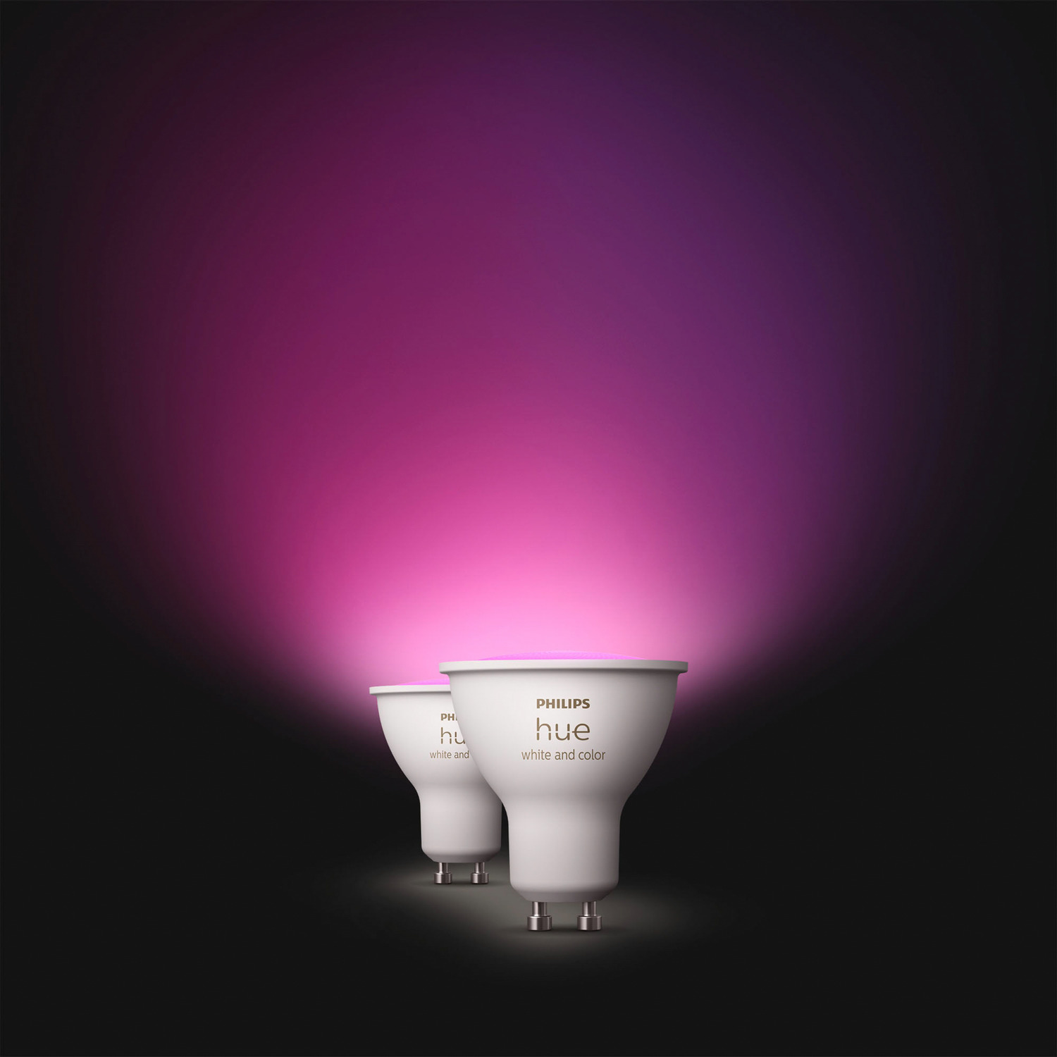 Deux ampoules intelligentes Philips Hue blanches sur fond noir, avec un dégradé rose et violet.