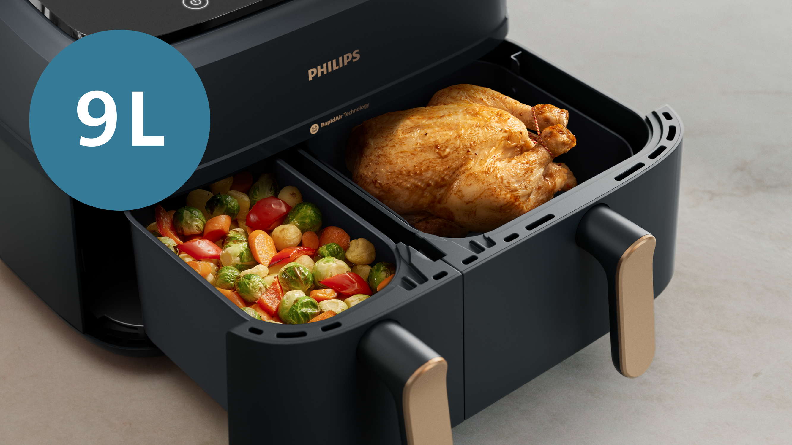 Una friggitrice ad aria con due scomparti, uno con un pollo arrosto, l'altro con verdure.