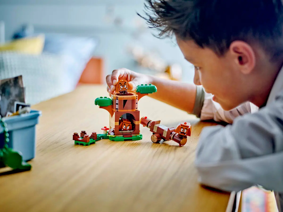 Dziecko bawiące się zestawem LEGO, przedstawiającym drzewo i postać.