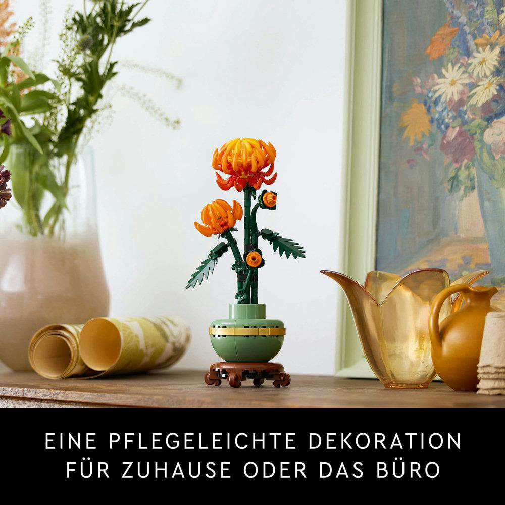 Ein Blumenarrangement in einer grünen Vase auf einem Holztisch, mit Blumenmalerei im Hintergrund.