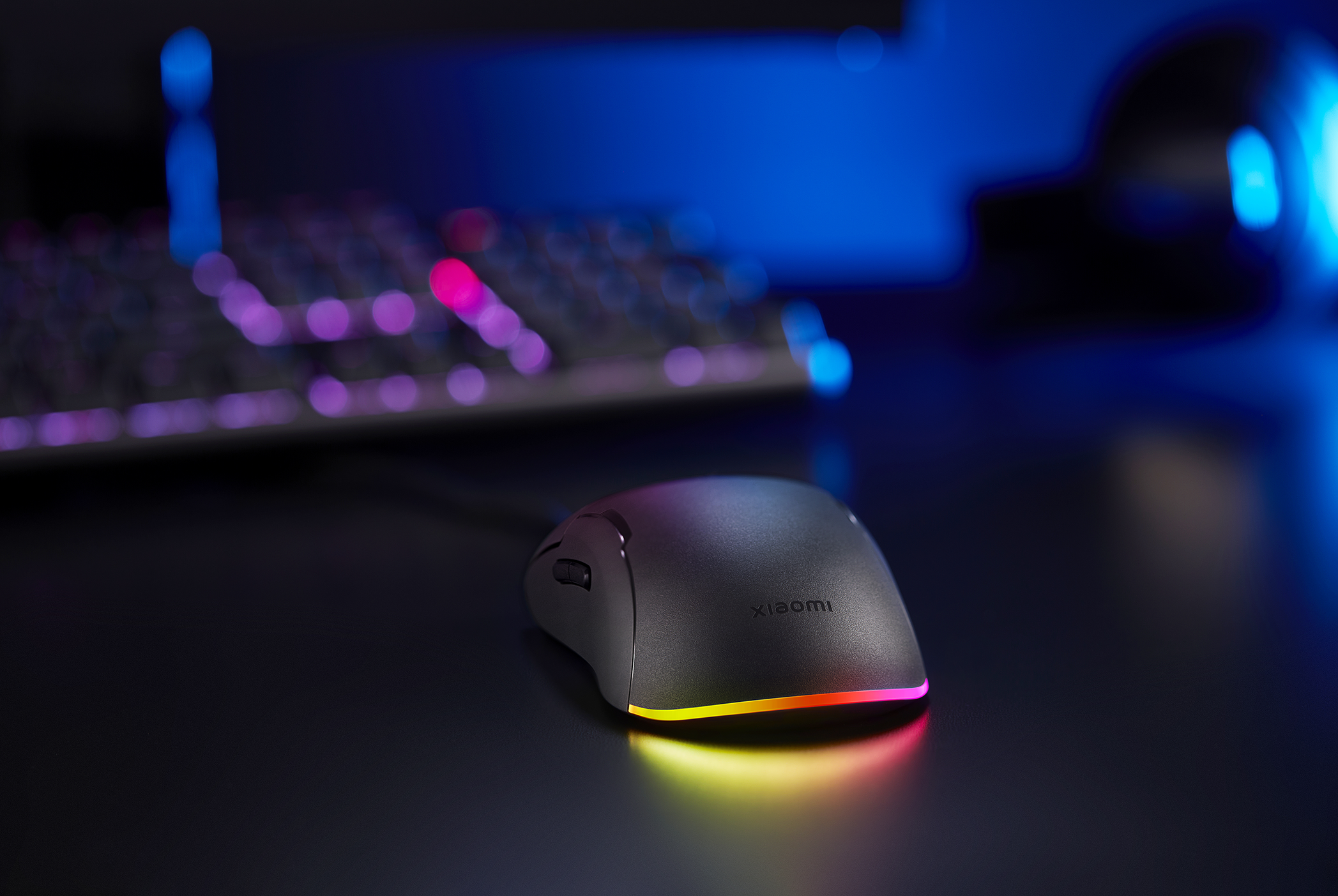 Fekete számítógépes egér RGB világítással az alján, sötét asztalon.