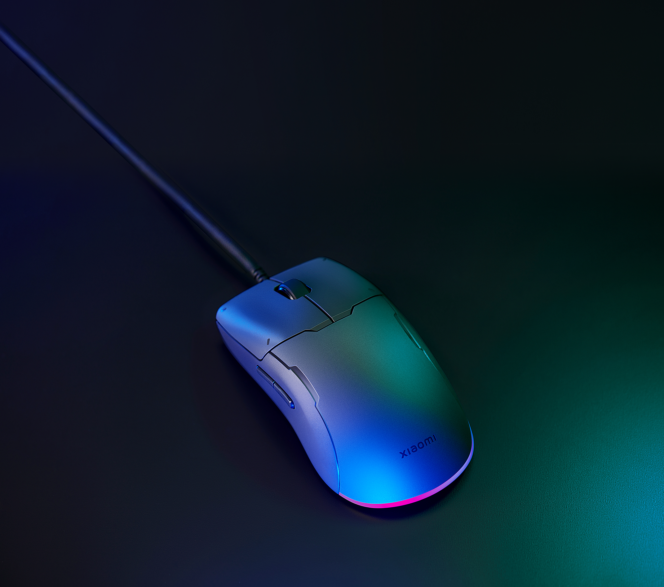 Szürke gamer egér színes fényekkel. Szöveg: Xiaomi. Fekete kábel csatlakoztatva.