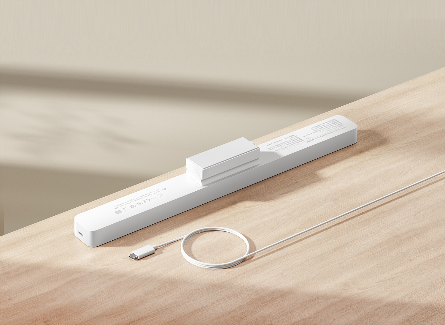 Egy fehér téglalap alakú töltő USB-C kábellel, fa felületen. Egy kis fehér blokk van rajta.