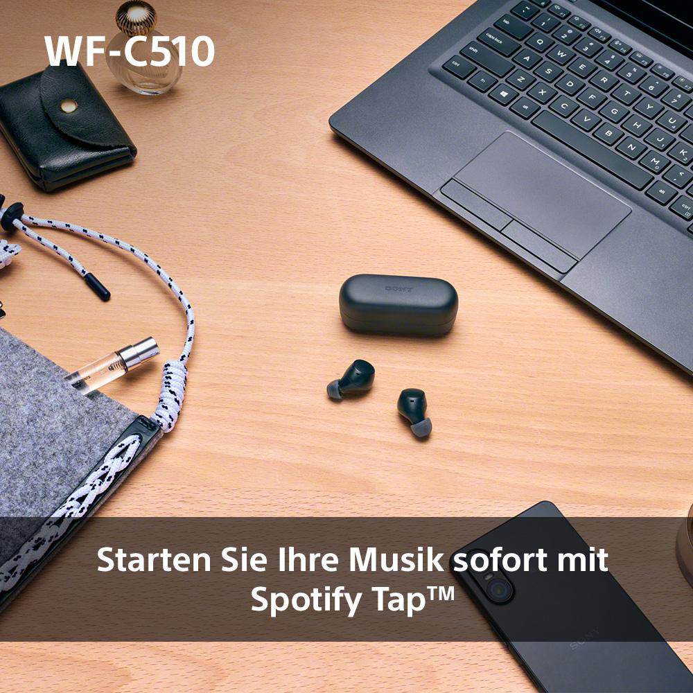 Ohrhörer und Ladecase. Laptop und Zubehör auf Holztisch. Text unten.