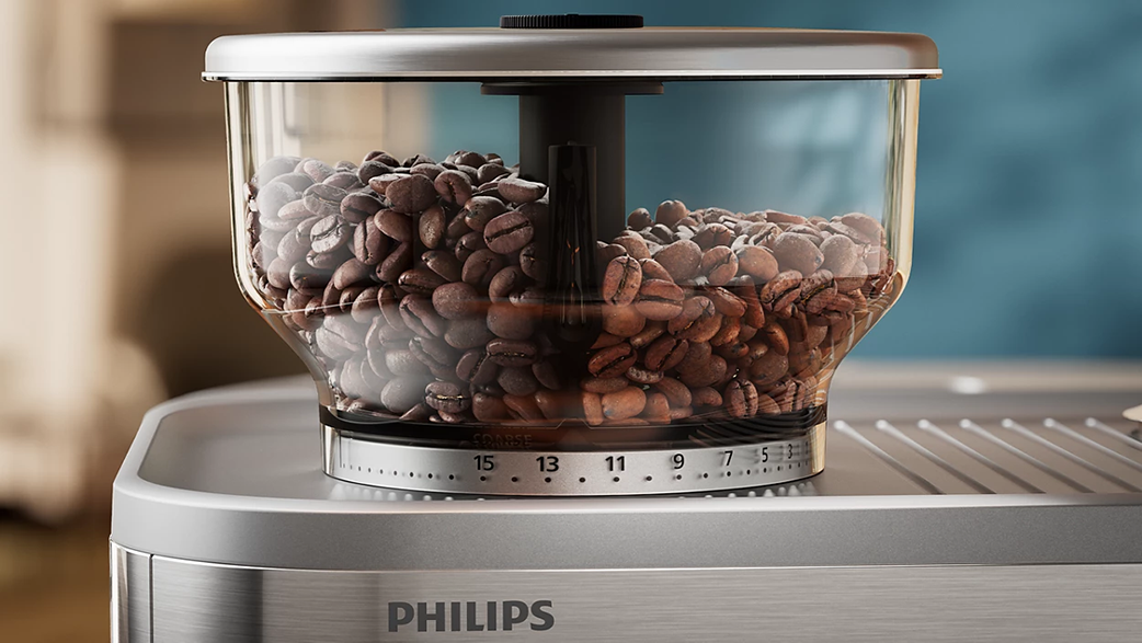 Egy Philips kávéőrlő kávébabbal. Az őrlő ezüstszínű, fekete tetővel.