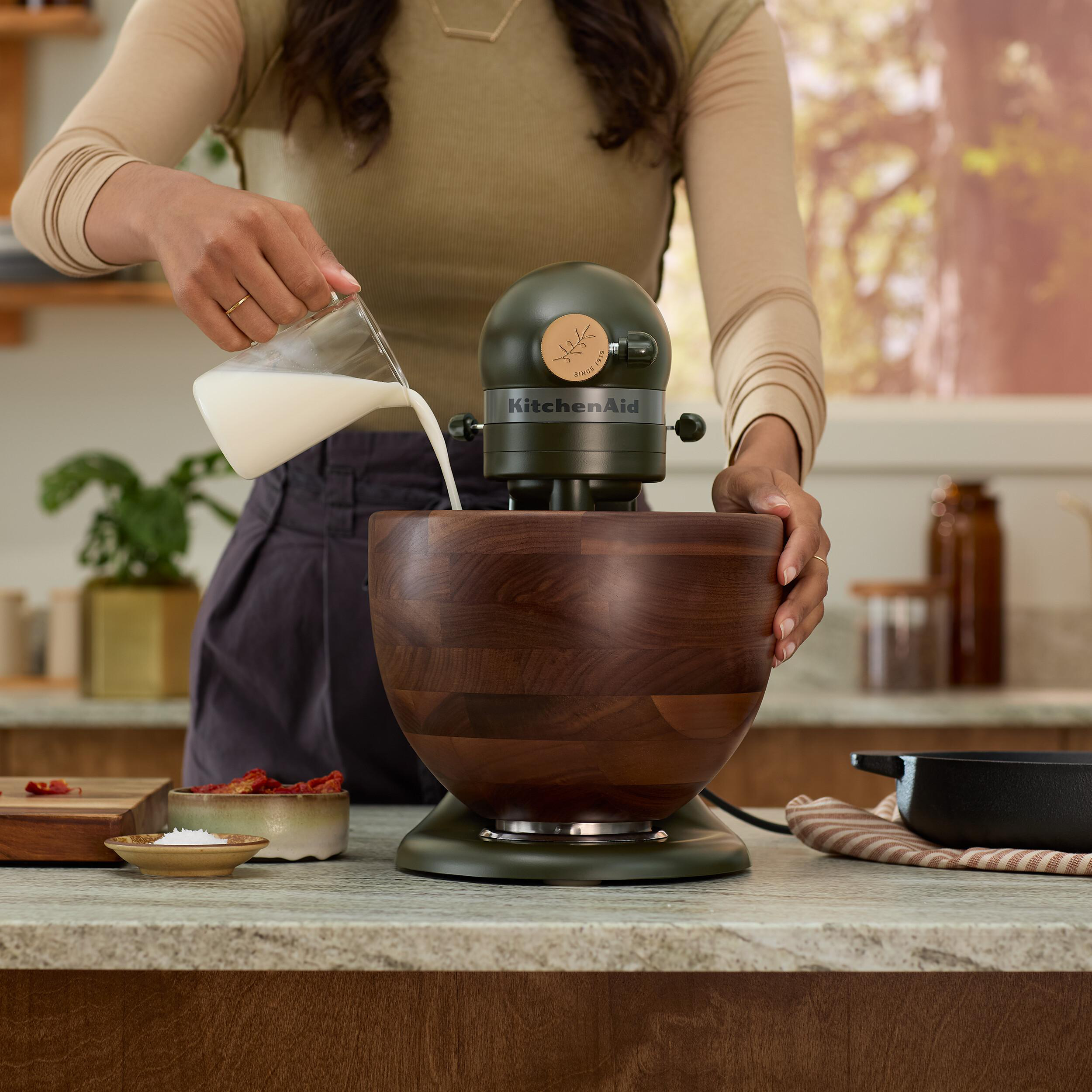 Person gießt Milch in eine KitchenAid-Mixerschüssel.