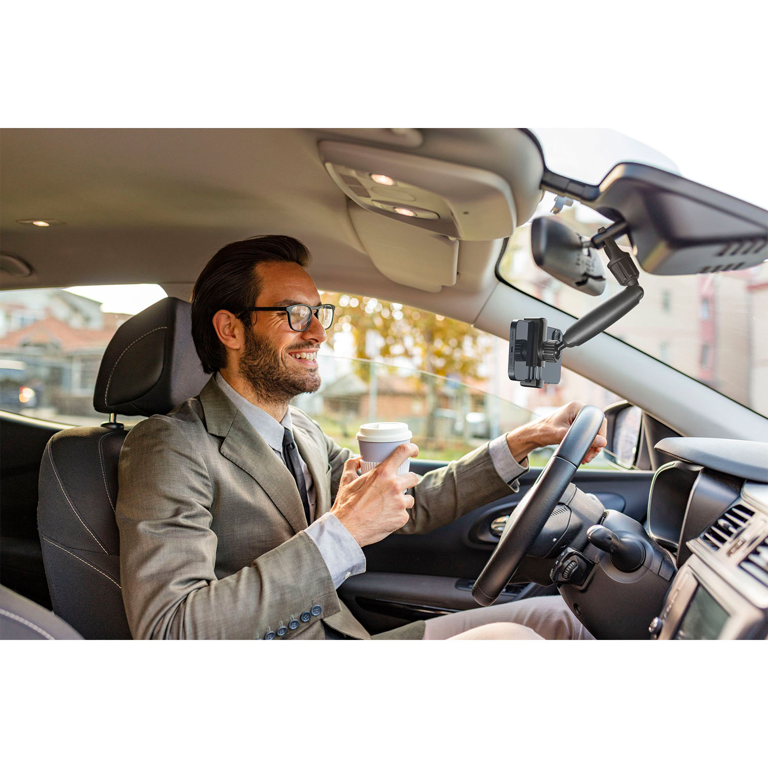 Uomo in auto, con in mano un caffè, che guarda avanti.