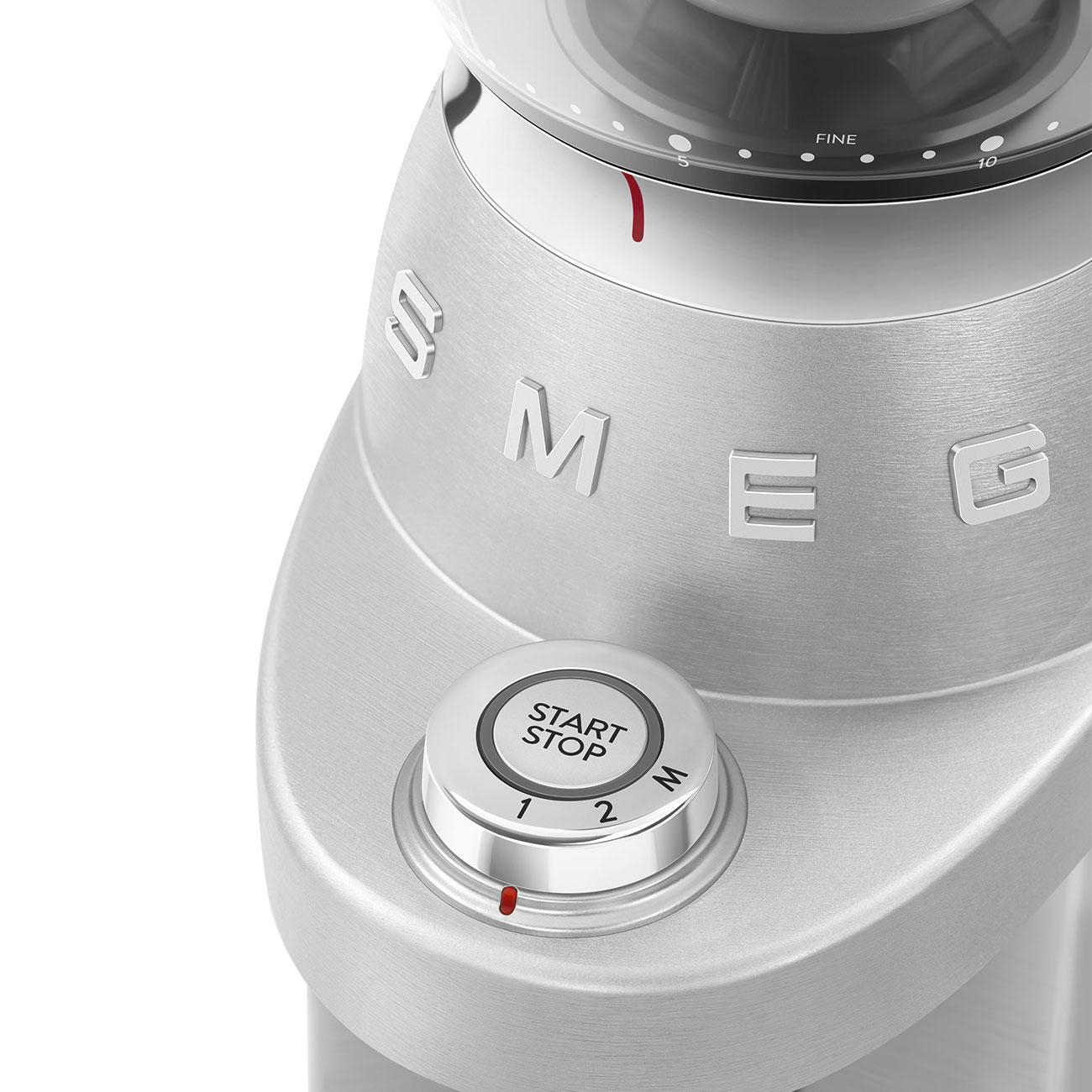 Nahaufnahme eines silbernen SMEG-Kaffeemahlers mit Start/Stopp-Taste und Drehknopf.