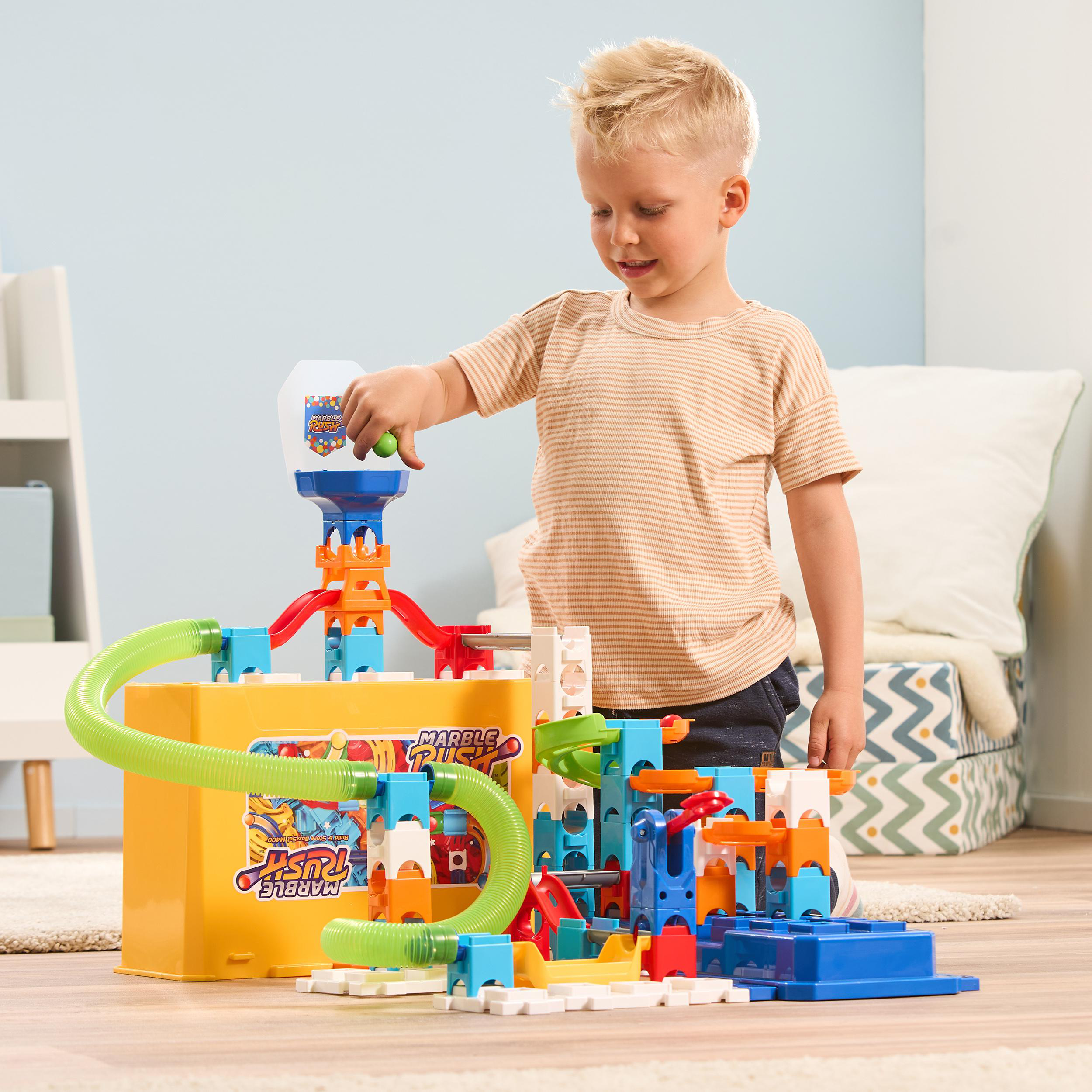 Ein kleiner Junge spielt mit einer Murmelbahn mit einer gelben Box.