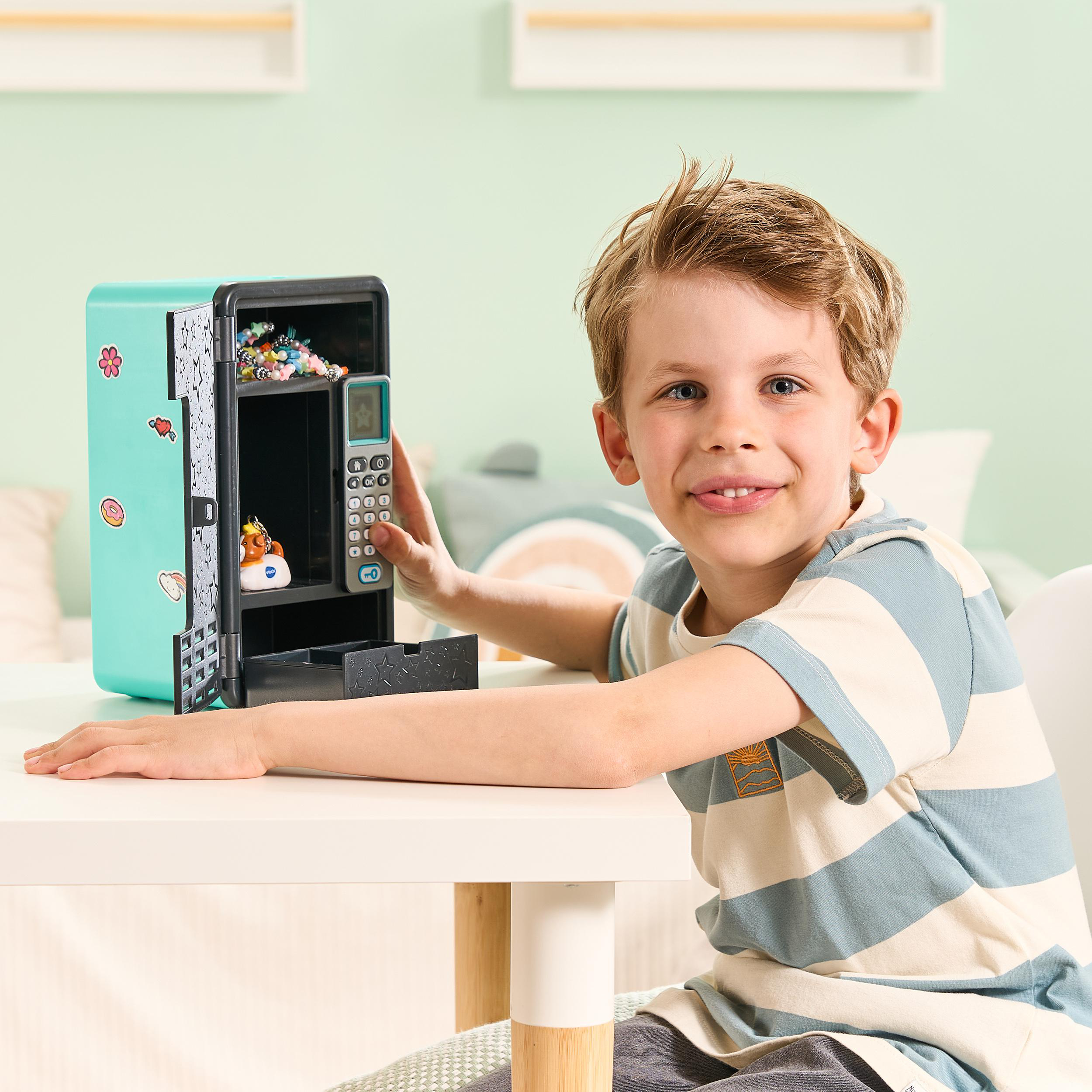 Ein Junge lächelt in die Kamera, während er einen Spielzeug-Verkaufsautomaten hält. Die Maschine ist offen.