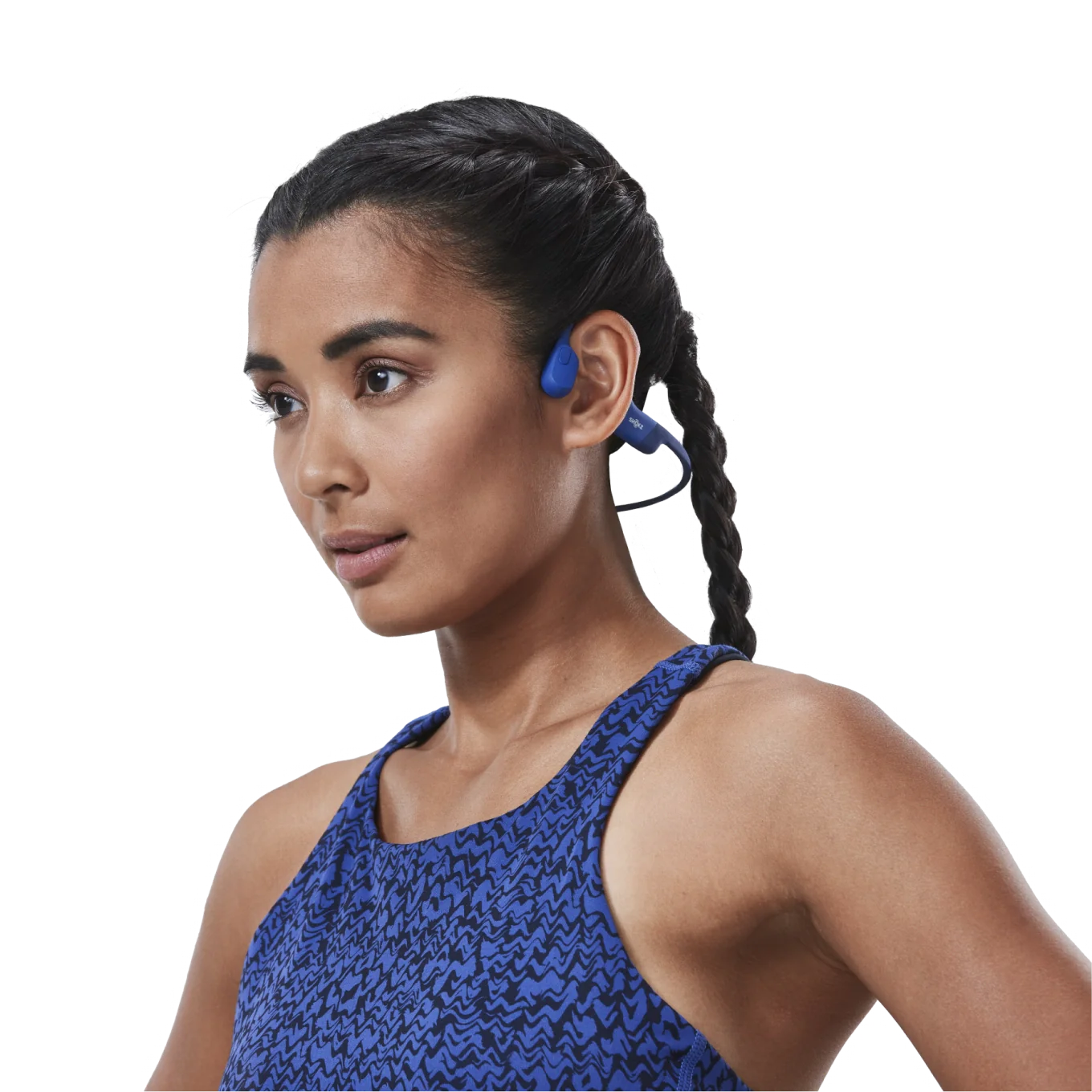 Femme portant un écouteur bleu. Elle court et sourit.