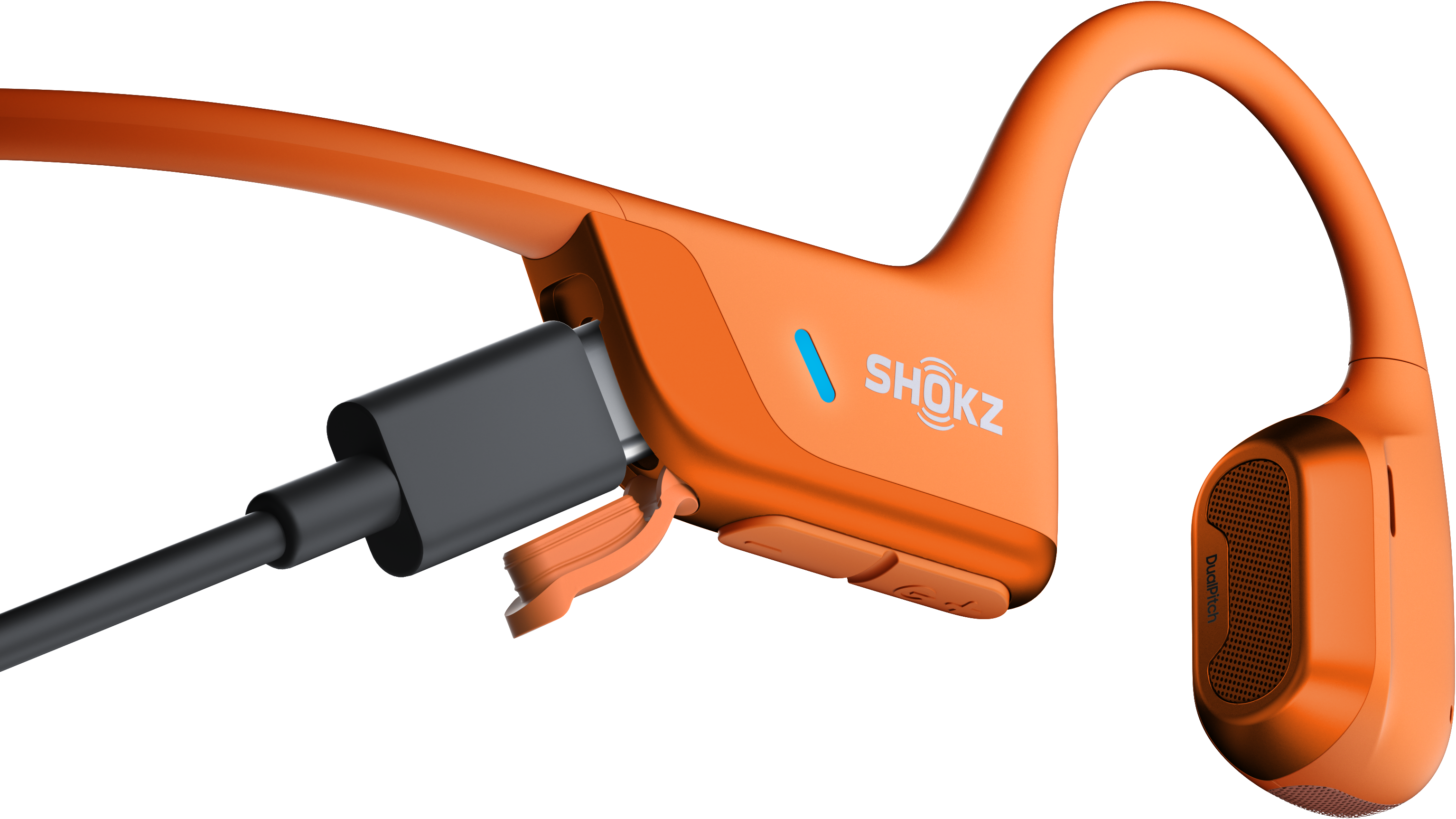 Écouteurs Shokz orange avec un câble de chargement connecté.