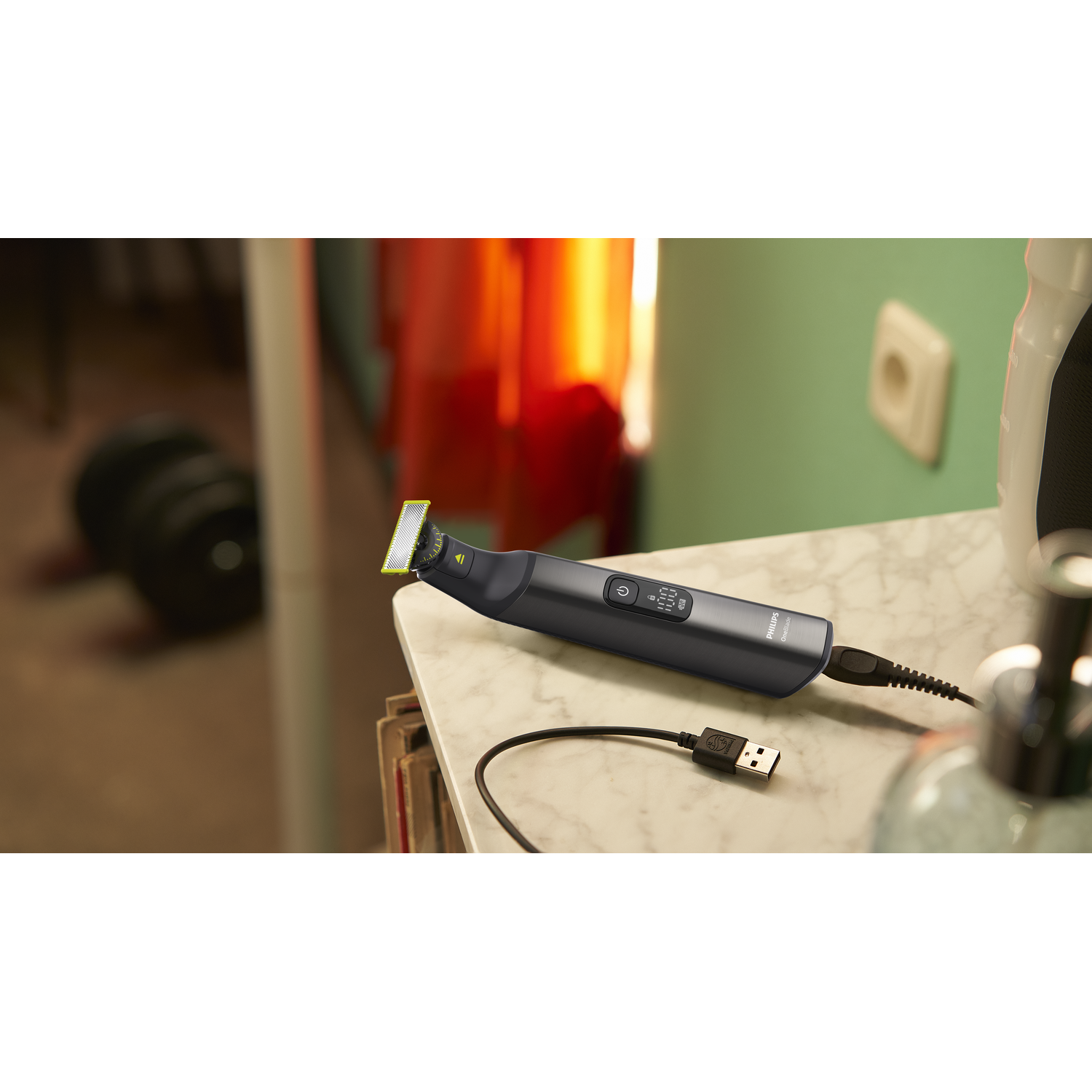 Black hair trimmer on a table. The trimmer is plugged into a USB cable.