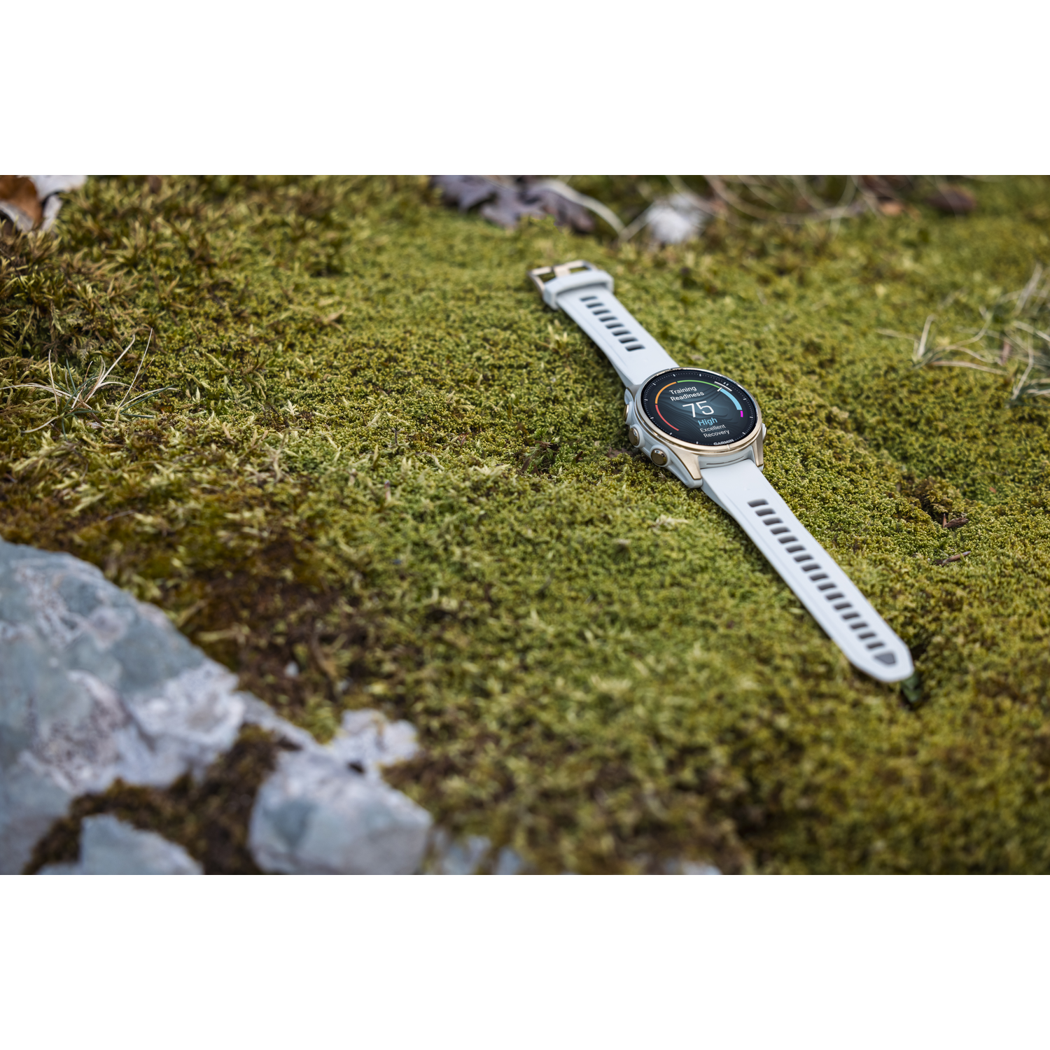 Een Garmin-horloge op een mosachtige ondergrond, met een hoge score, met een witte horlogeband.