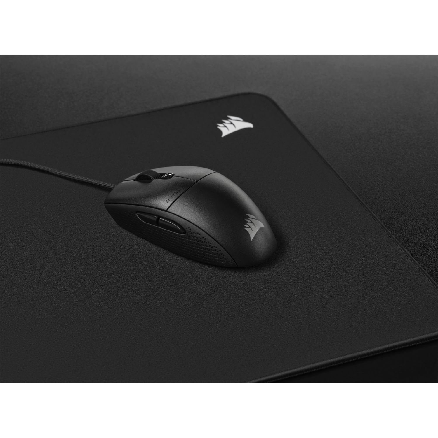 Black mouse on a black mousepad. The mouse has a curved design and a logo.