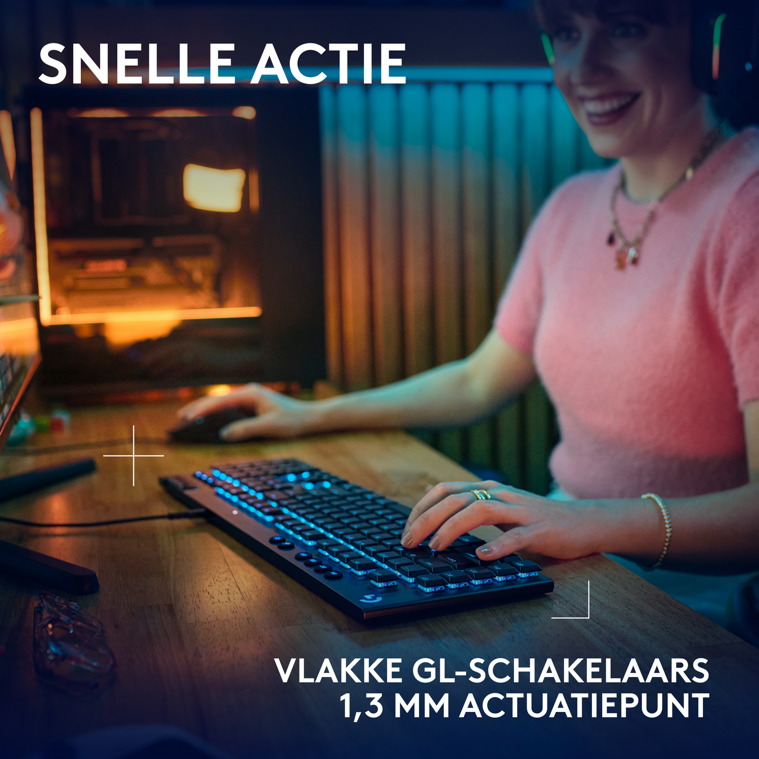 Woman gaming, using keyboard with blue lights, smiling. Mouse on the left. Wooden table.