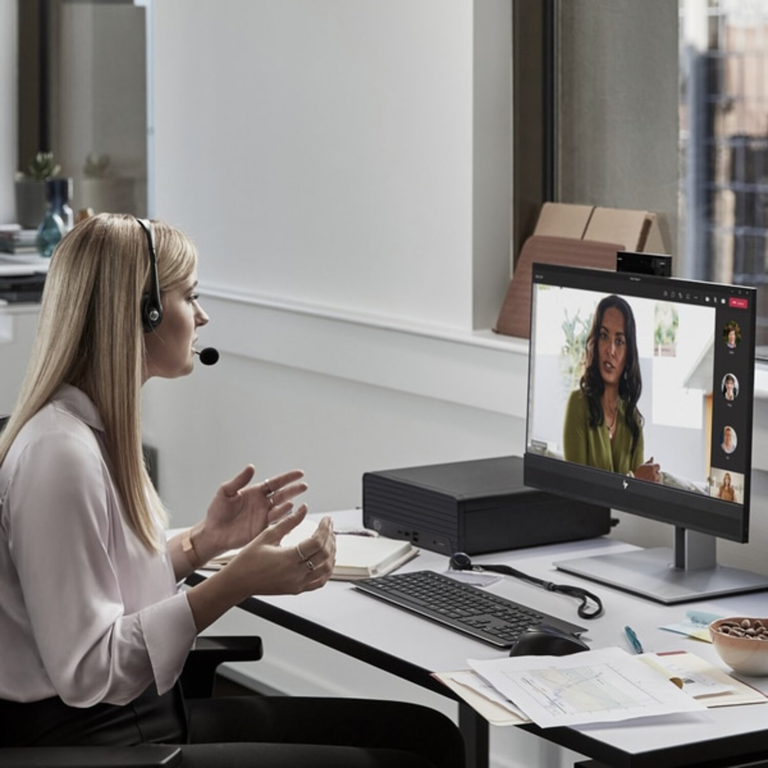 Een vrouw is in een videogesprek op een computer. Ze draagt een headset en is aan het interageren.