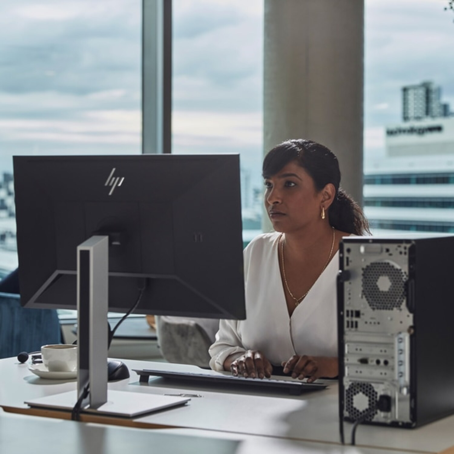 Vrouw werkt aan een bureau, kijkt naar een computerscherm, met een desktop.