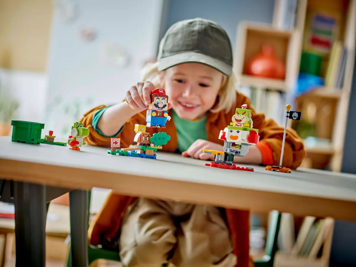 Dziecko bawiące się figurkami Lego Mario na stole z klockami.