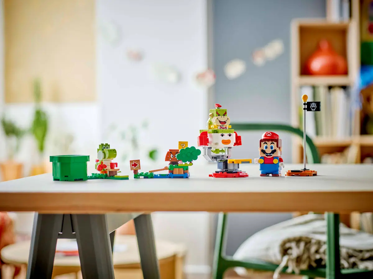 Zestaw Lego Mario na drewnianym stole. Figurka Mario, Yoshi, klocki i flaga w ekspozycji.