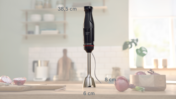 Arka planda boyutları gösterilen siyah ve gümüş renkli bir el blenderi.