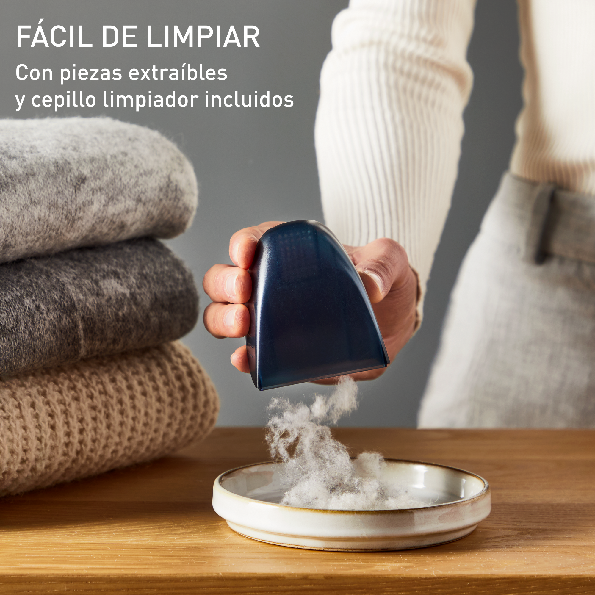 Persona limpiando un suéter con un quitapelusas, con un cuenco de pelusa.