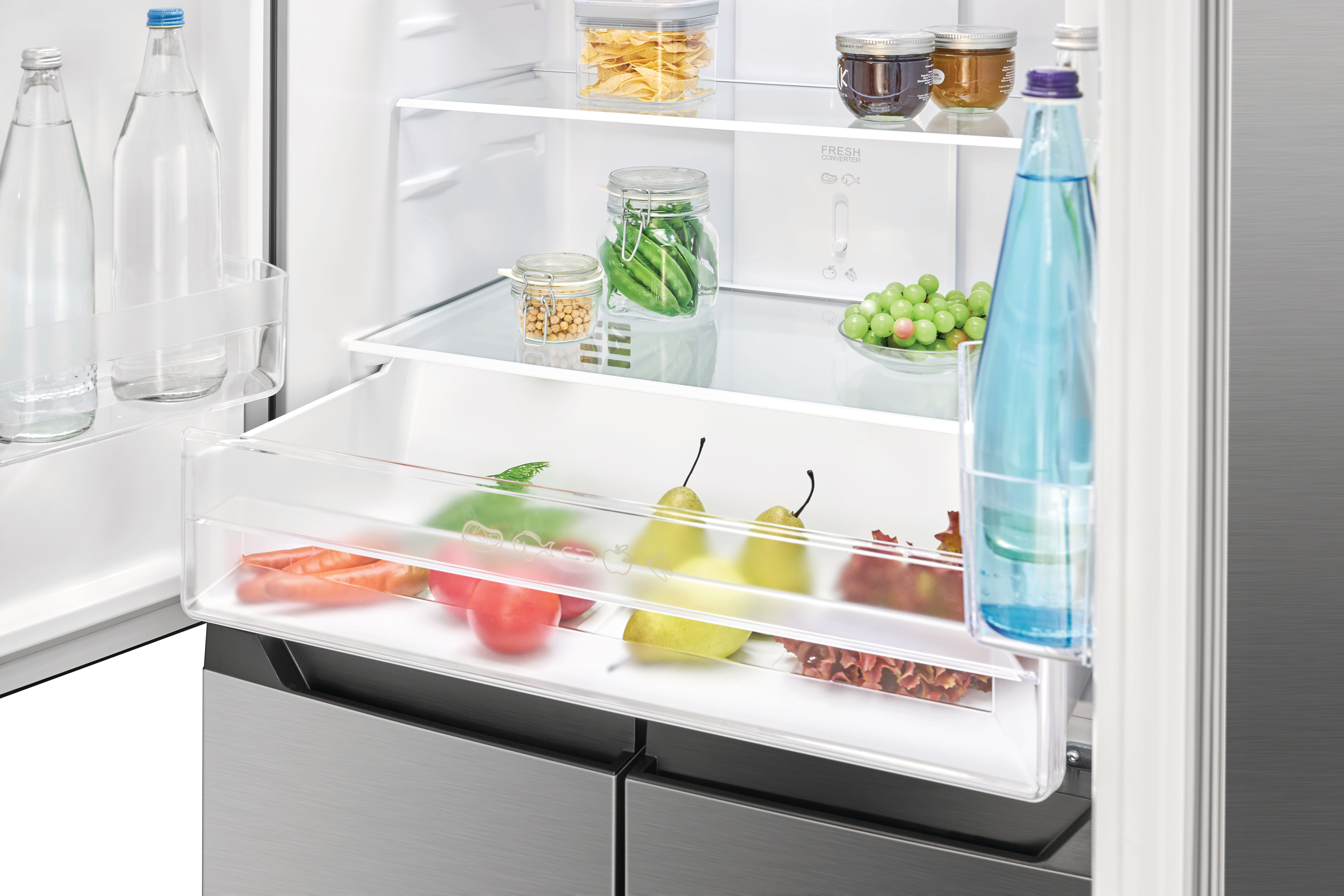Ein offener Kühlschrank mit Regalen voller Lebensmittel. Es gibt Wasserflaschen, Früchte und Gläser mit Essen.