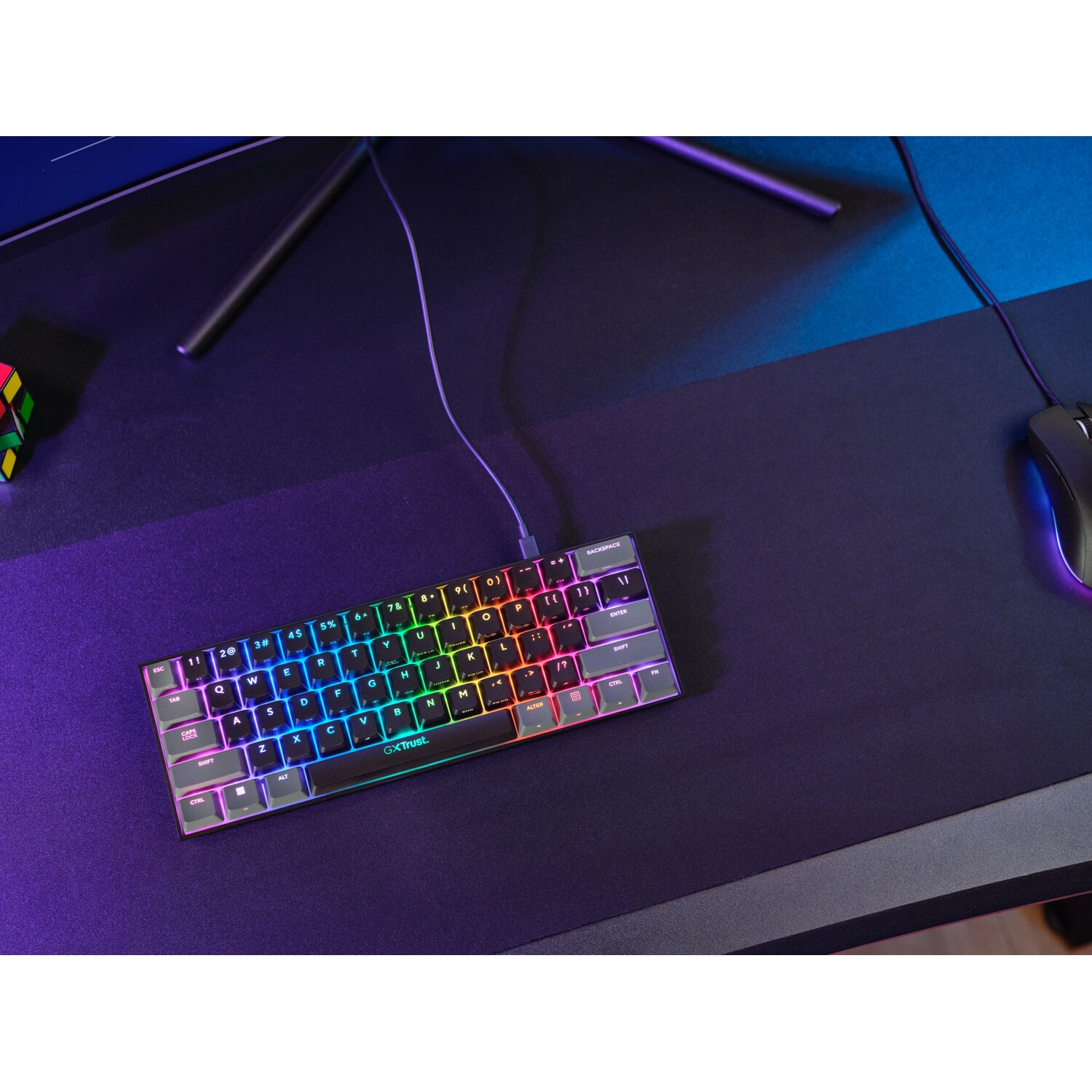 A small, multi-colored keyboard with an illuminated rainbow effect on a black surface.