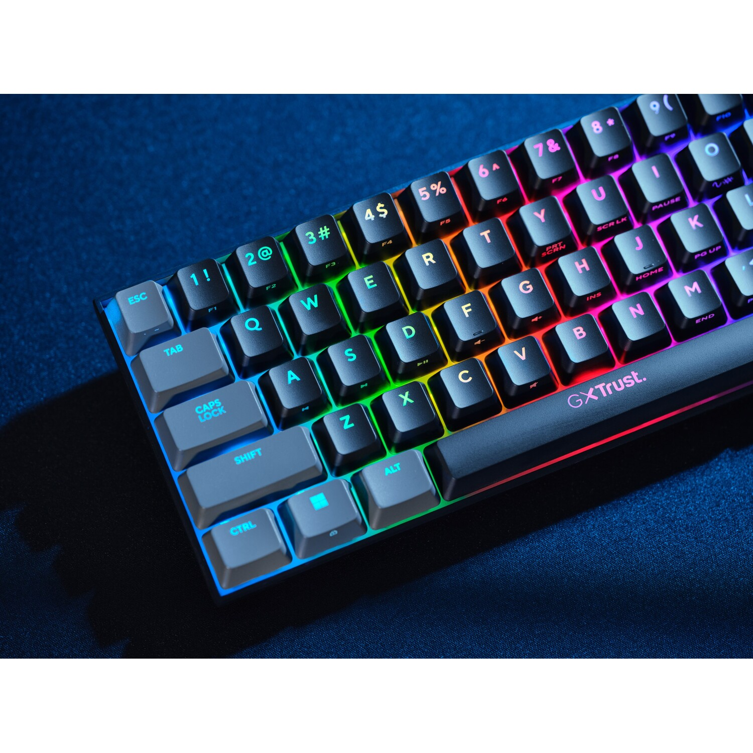 A close-up of a keyboard with colorful backlit keys on a dark blue surface.