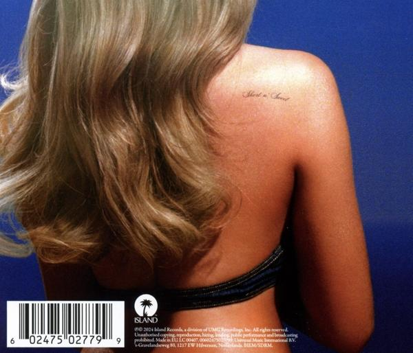 Der Rücken einer Frau mit blonden Haaren, einem Schulter-Tattoo und blauem Hintergrund.