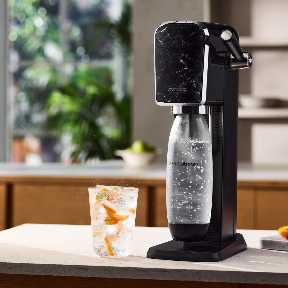Machine SodaStream avec un verre de boisson fruitée, bulles et un design noir marbré.