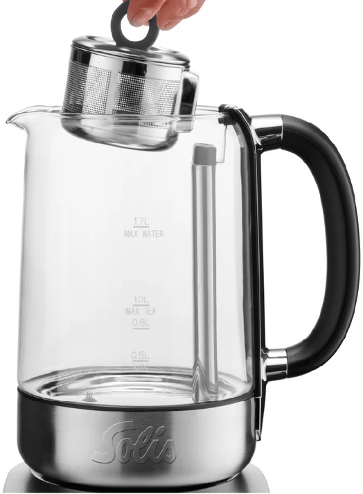 Une théière en verre avec une poignée noire et une main retirant l'infuseur en acier.