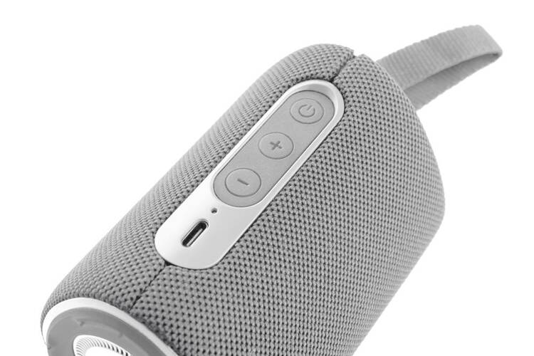 Zbliżenie szarego głośnika z przyciskami głośności i portem.