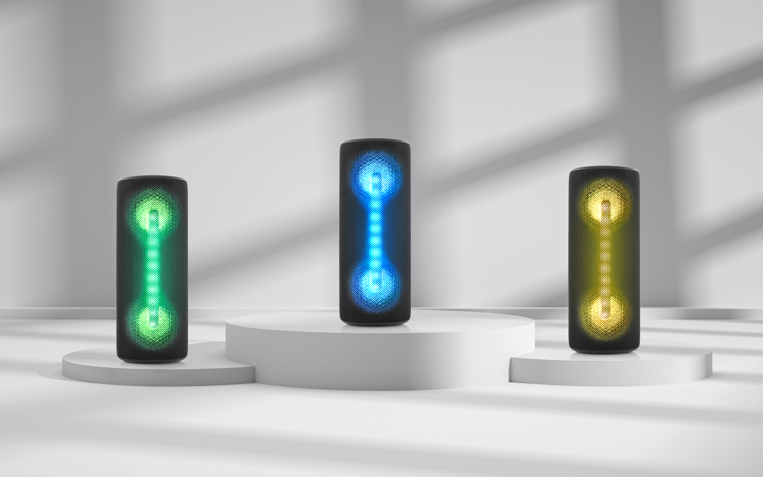 Trzy głośniki z żywymi wyświetlaczami świetlnymi, stojące na białej platformie.