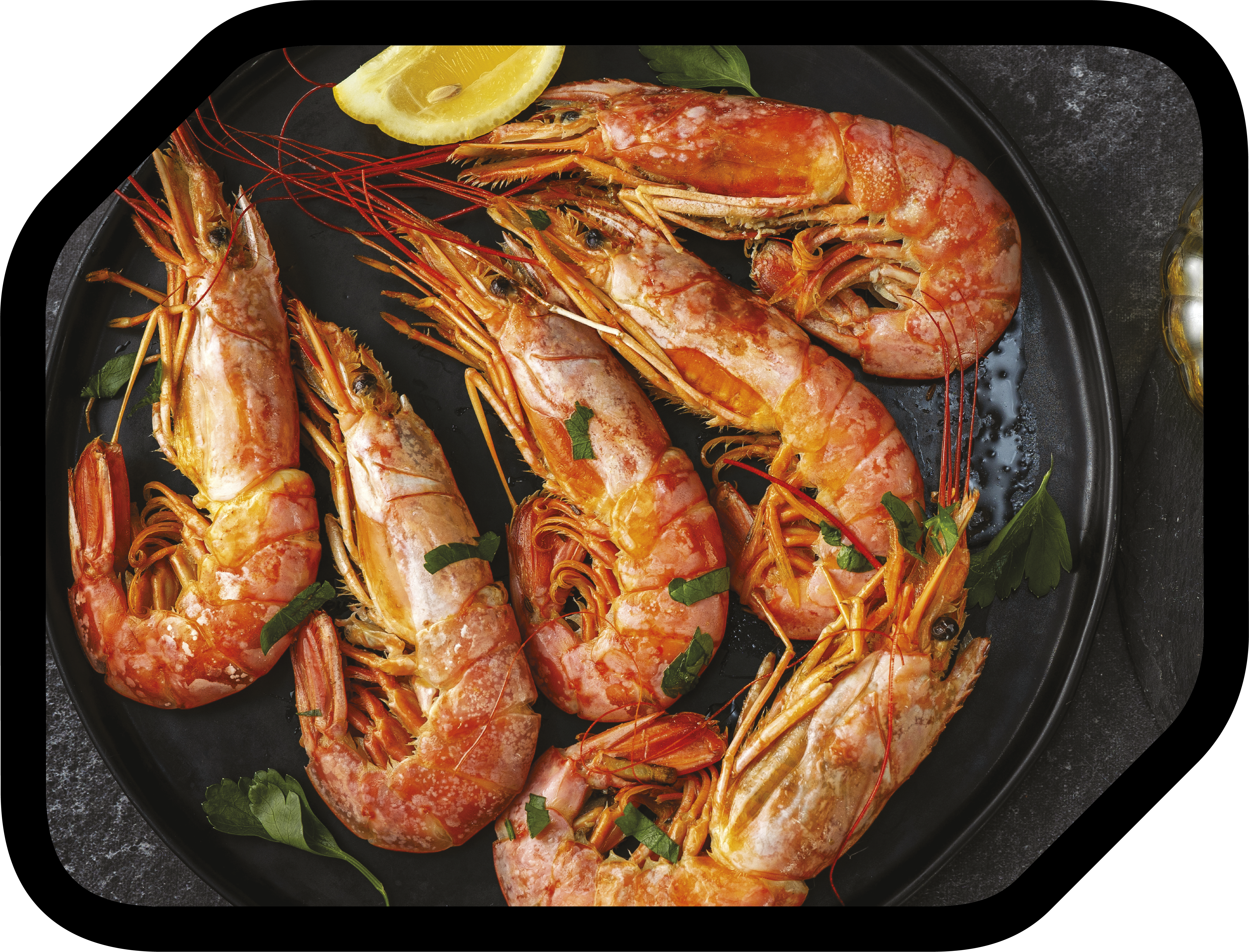 Une assiette avec des crevettes cuites, garnies de persil et d'une tranche de citron, prêtes à servir.